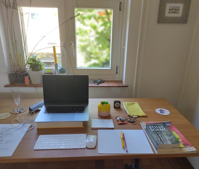 Schreibtisch mit Laptop, Unterlagen und dem Buch Stille Scham